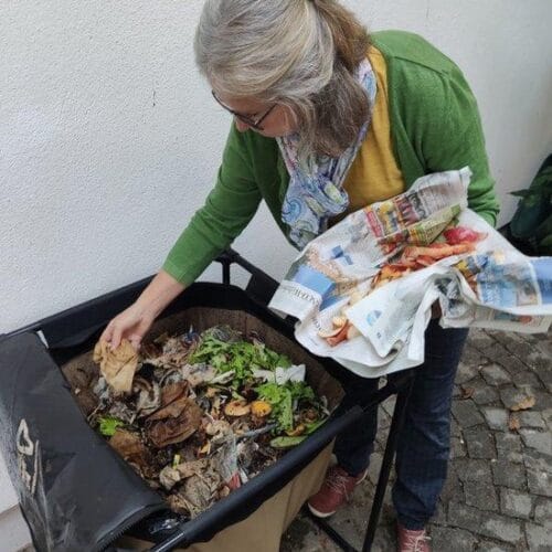 Vrouw die groente- en fruitafval toevoegt aan de Urban Worm Bag voor compostering.