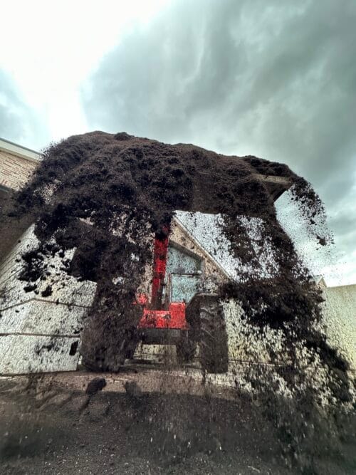Wormcompost losgestort door een rode telescooplader.